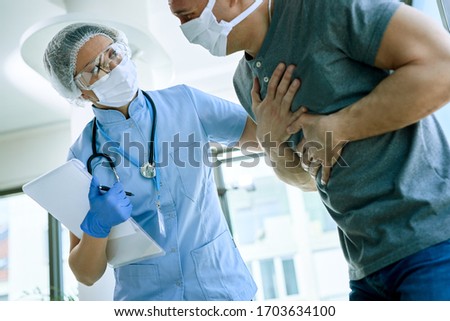 Female doctor with a patient who is complaining of chest pain during coronavirus epidemic.  Royalty-Free Stock Photo #1703634100