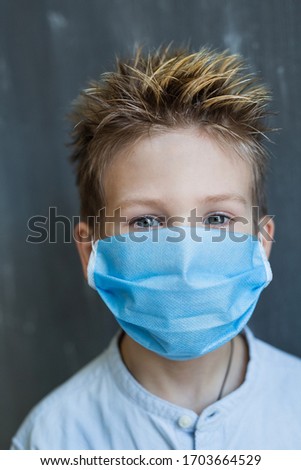 Cute blonde boy in blue medical mask against virus.