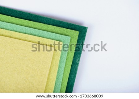 Yellow and green palette of felt material stacked on a white background
