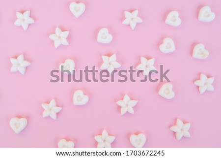 Top view on sugar in the shape of heart and flower on a pink background