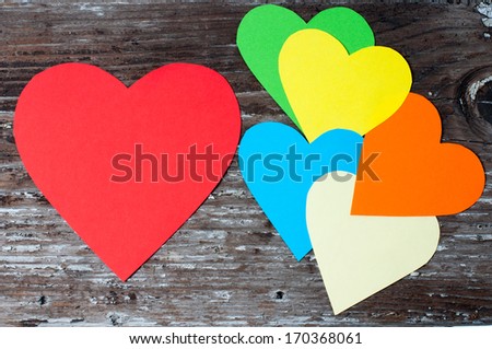 Different color paper hearts on an old wood