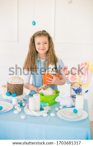 Cute teenage girl in jeans with an Easter rabbit in a bright spring room near the Easter table. Happy easter