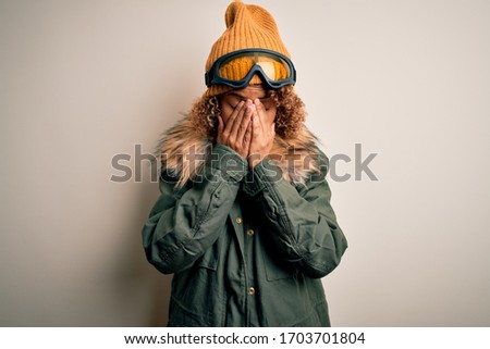 Young african american skier woman with curly hair wearing snow sportswear and ski goggles rubbing eyes for fatigue and headache, sleepy and tired expression. Vision problem