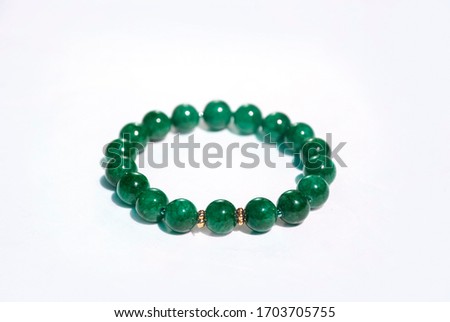 Natural shiny stone bracelet isolated on white background. Green emerald stones with 24k gold flowers for spring and summer time. Luxury jewellery for party or wedding