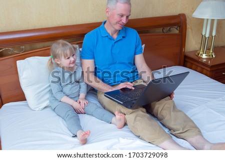 Happy father and daughter laying on bed and using laptop at home, watching videos, Happy Father's day. Selective focus.