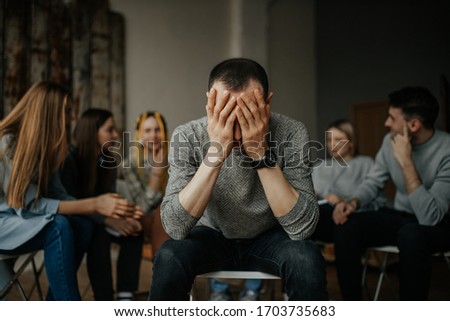 young caucasian man tired of drinking alcohol or drugs, members of anonymous alcoholics club gathered to share experience of getting rid of problem. guy close face with hands. help, support concept Royalty-Free Stock Photo #1703735683