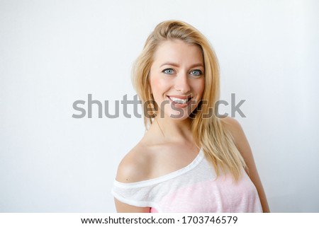 Pretty smiling joyfully female with fair hair, looking with satisfaction at camera, being happy. Studio shot of good-looking beautiful woman isolated against blank studio wall.