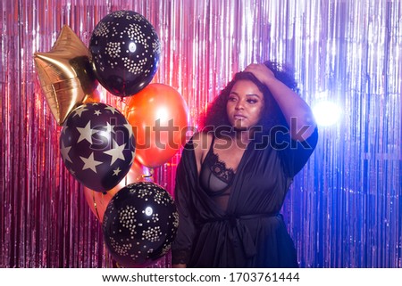 Young black woman looks happy while spend time in night club. Birthday party and nightlife concept.