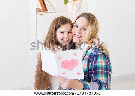 Mother's Day and family holidays - Mother reading greeting card from her daughter.