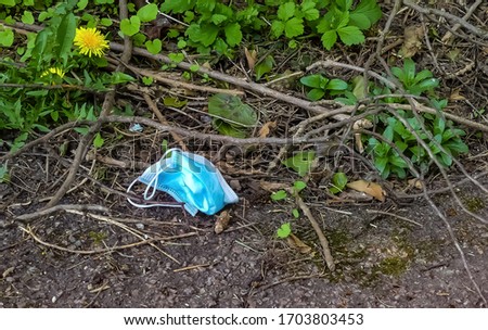 Carelessly discarded medical face mask thrown away on a public footpath during Coronavirus (COVID-19) pandemic. Banbury. Oxfordshire. Landscape image with space for copy. England.  Royalty-Free Stock Photo #1703803453