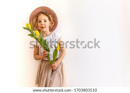 
Lifestyle portrait of happy playful little child girl holding bouquet  yellow tulips as gift for mother's day father's day birthday anniversary cutout on white background copy space. Summer vacation.