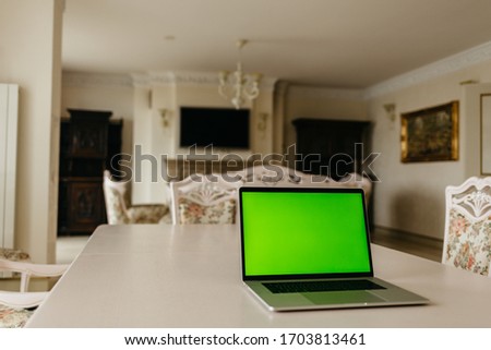Laptop computer with green screen in room