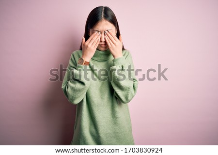 Young beautiful asian woman wearing green winter sweater over pink solated background rubbing eyes for fatigue and headache, sleepy and tired expression. Vision problem