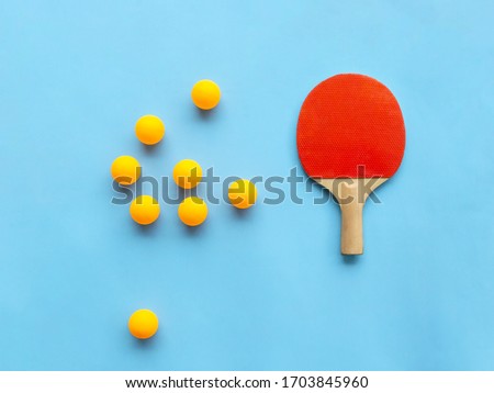 Red racket for table tennis with yellow balls on blue background. Ping pong sports equipment in minimal style. Flat lay, top view, copy space Royalty-Free Stock Photo #1703845960