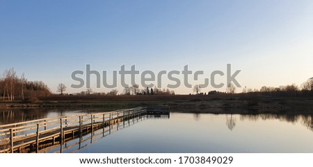 Pond at golden hour with beautiful orange sky. With wooden bridge