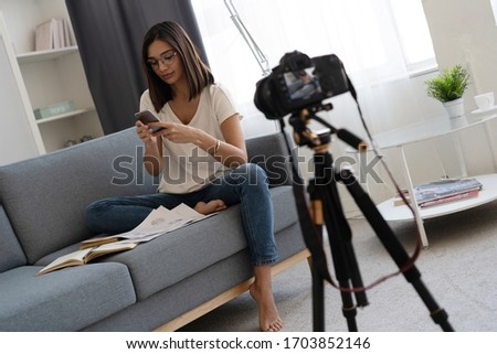 Young and smart. Beautiful young woman in casual wear smiling while recording video at home. Prevent infection from the pandemia. Healthy at home.