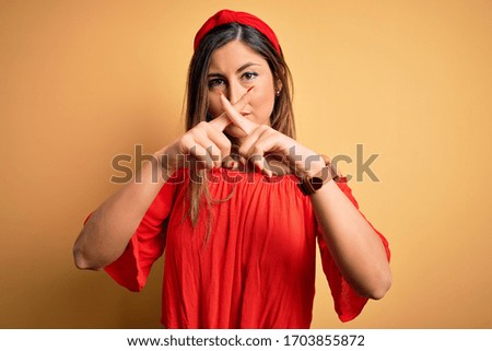 Young beautiful woman colorful summer style over yellow isolated background Rejection expression crossing fingers doing negative sign