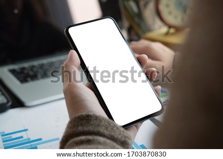Woman using smartphone with blank screen for business financial work at home