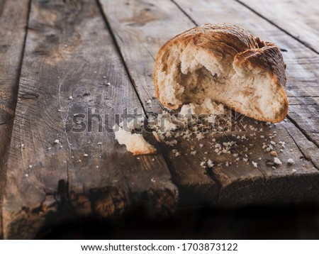 bread roll which has been bitten and eaten by someone, isolated on a very old wooden table, poverty and hunger concept, financial crisis concept Royalty-Free Stock Photo #1703873122