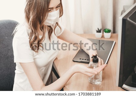 A young woman in a medical respiratory mask washes her hands with an antiseptic, alcohol solution, antibacterial spray, gel, coronavirus protection, hand hygiene, quarantine