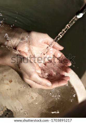 Female hands collecting pure water from a natural spring .