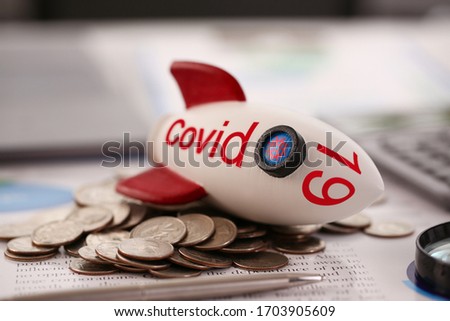 Rocket with inscription Covid 19 fell on a pile of coins close-up background. World financial crisis concept
