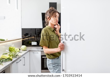 Woman looking into the fridge while cooking healthy food on the modern kitchen at home Royalty-Free Stock Photo #1703923414