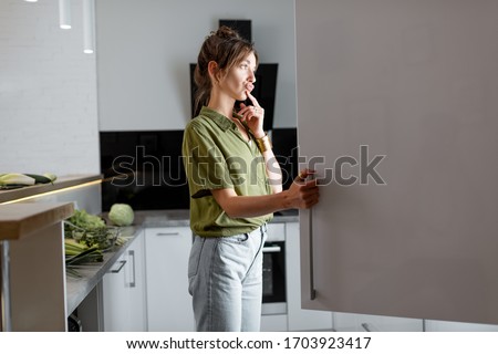 Young woman looking into the fridge, feeling hungry at night Royalty-Free Stock Photo #1703923417