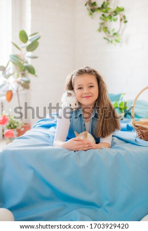 Cute teenage girl in jeans with an Easter rabbit in a bright spring room decorated for Easter. Happy easter