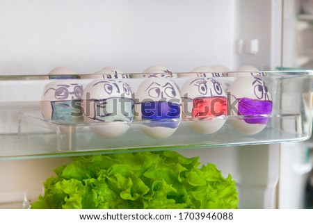 Easter eggs on the theme of coronavirus, painted funny masked faces on Easter eggs, decorated for Easter, in a refrigerator on a shelf