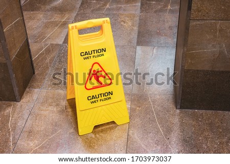 Yellow sign caution wet floor with a falling man in the hallway of the public toilet