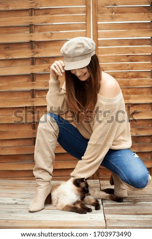 Middle-aged Caucasian woman in a wooden environment, in the afternoon playing with a cat in a relaxing moment