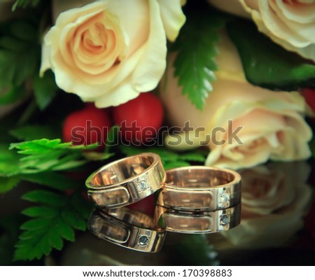 Golden wedding rings with bouquet. Focus on the rings