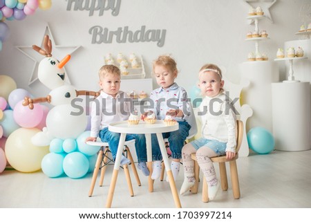 Cute little boys and girl at a table with birthday cakes at a children's party with balloons. Children's party. Balloons