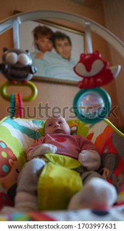 Portrait of just born baby in pink blouse lying in a cradle under parents photo on the wall