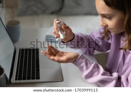 Teenage girl sit at desk clean disinfect hands with gel sanitizer protect from coronavirus covid-19 pandemic, pupil sanitize take care of body hygiene with antibacterial liquid, corona virus concept Royalty-Free Stock Photo #1703999113