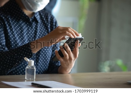 Close up of woman protect from coronavirus disinfect smartphone with sanitizer, female employee cleanse sanitize cellphone gadget with antibacterial liquid, COVID-19 pandemic, corona concept Royalty-Free Stock Photo #1703999119