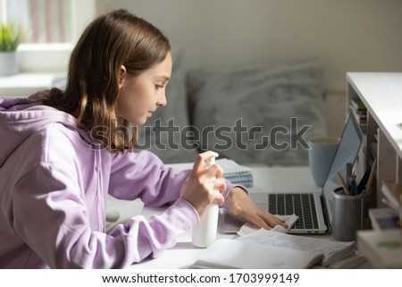Pupil disinfect laptop with gel sanitizer take care of hygiene during coronavirus pandemic, teenage girl sanitize computer workplace with antibacterial liquid protect from covid-19, corona concept Royalty-Free Stock Photo #1703999149