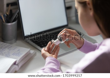 Close up of girl pupil clean disinfect hands at desk with sanitizer protect from corona virus covid-19 pandemic, teenager sanitize take care of hygiene with antibacterial gel, coronavirus concept Royalty-Free Stock Photo #1703999257
