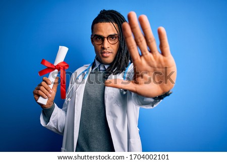 African american doctor man with dreadlocks wearing stethoscope holding diploma degree with open hand doing stop sign with serious and confident expression, defense gesture