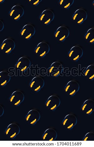 Pattern. Headphones with sunflowers hover in the air. On a black background. A concept on the theme of summer and music.