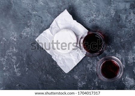 Glass of red wine served with cheese camembert over dark texture background. Top view, flat lay. Copy space