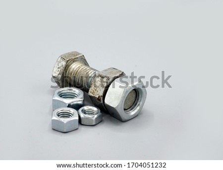 Stainless steel screws and nuts isolated on gray background. New and shiny chrome screws and nuts. Copy space.