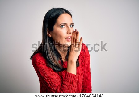 Young brunette woman with blue eyes wearing casual sweater over isolated white background hand on mouth telling secret rumor, whispering malicious talk conversation