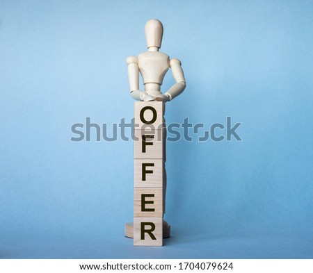 Wooden man stands behind word OFFER written on wooden cubes on light blue background