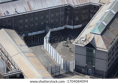 An aerial view of a HMP prison taken from a helicopter in the United Kingdom. The old grey Her Majesties Prison has fences and barbed wire preventing the escape of the jails inmates Royalty-Free Stock Photo #1704084094
