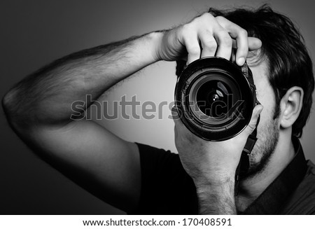 Young man with professional camera. Monochrome portrait