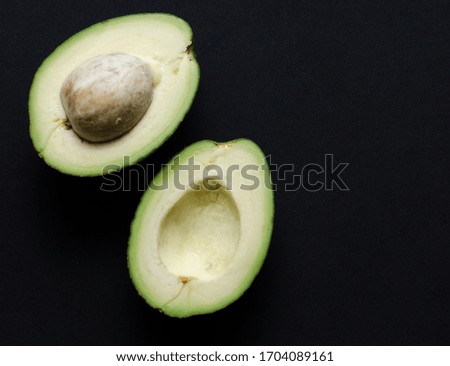 halves of ripe green avocado on a black background
