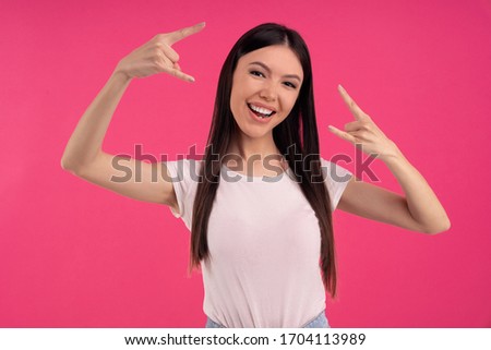 Pleasant looking cheerful woman make rock sign, gestures with both hands, feels rebellious, shows heavy metal, goes wild, listens loud music at home, dressed casually. Asian girl has fun at party.