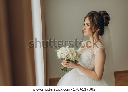 ￼￼ bride looks to the side of the screen and holds a bouquet in her hands